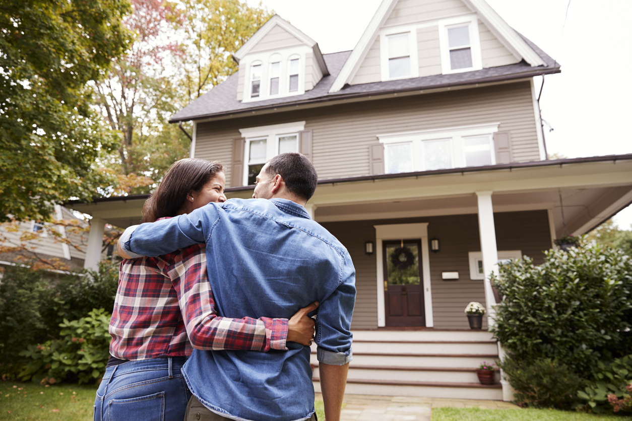 Couple standing in front of their new home